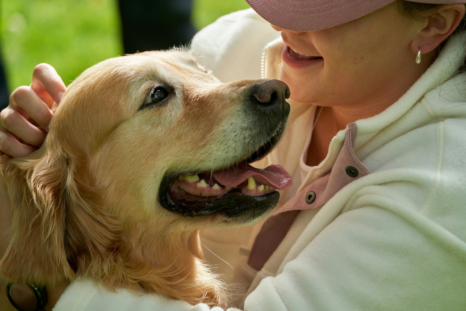 A smiling woman scratches the ears of a happy golden retriever.